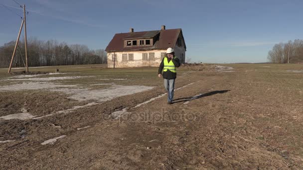 Trabalhador falando ao telefone perto de casa abandonada — Vídeo de Stock