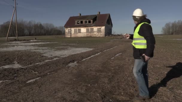 Stavební dodavatel počítá peníze poblíž opuštěného domu — Stock video