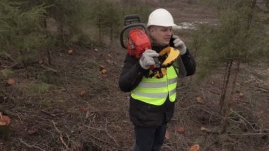 İşçi dik orman yamaç telefonla konuşurken omuz chainsaw ile