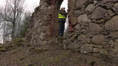 Eski tuğla duvar yakınındaki telefonda konuşurken bina müfettişi