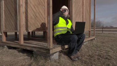 Oturup, kahve içme ve dizüstü bilgisayar kullanarak inşaat mühendisi