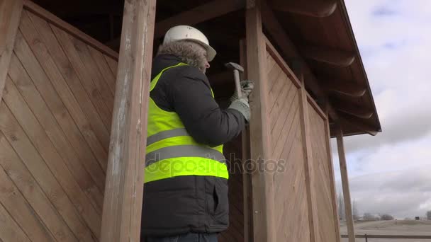 Worker hammering nail in wooden board — Stock Video