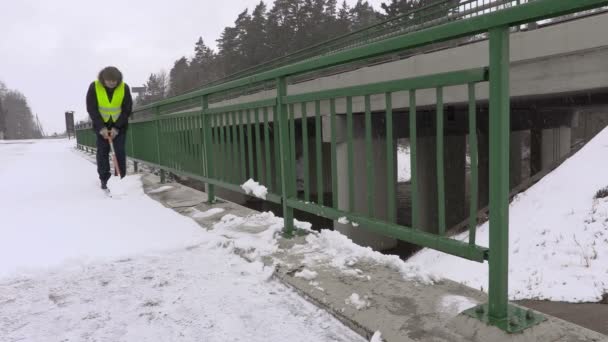 Vaktmästare med snöskyffel ta bort snö från bron — Stockvideo