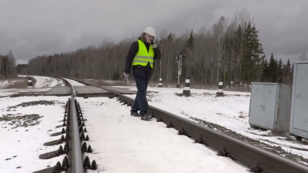 Trabajador del ferrocarril hablando por teléfono cerca de recintos eléctricos — Vídeo de stock