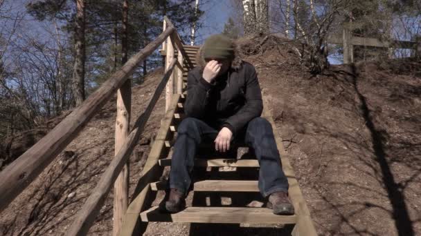 Depressieve man zit op houten trappen — Stockvideo