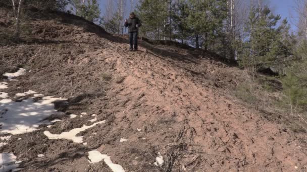 Hombre con bastones de senderismo bajando de la colina — Vídeo de stock