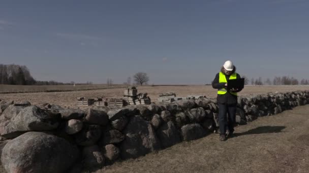 Будівельний інспектор використовує ноутбук біля кам'яної стіни — стокове відео