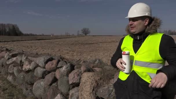 Будівельний інспектор п'є каву біля кам'яного паркану — стокове відео