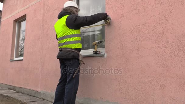 Construtor usando fita métrica perto da janela — Vídeo de Stock