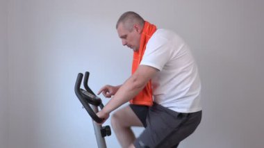 Bir havlu üzerinde egzersiz bisikleti ile mutlu adam