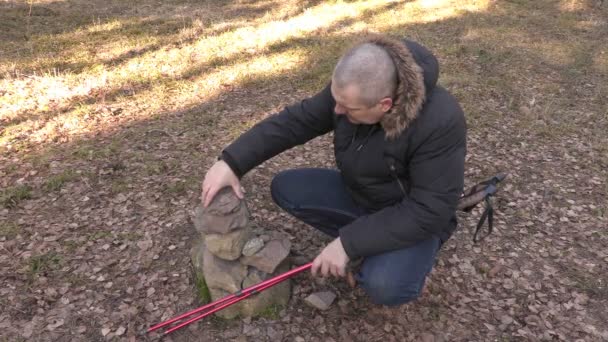 Hombre con bastones de senderismo balanceando piedras en el parque — Vídeos de Stock