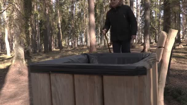 Homme avec bâtons de randonnée jeter du papier dans un conteneur à déchets — Video