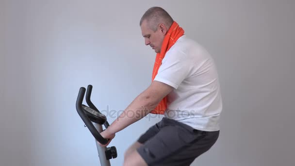 Hombre cansado limpiando con toalla en bicicleta estática — Vídeo de stock