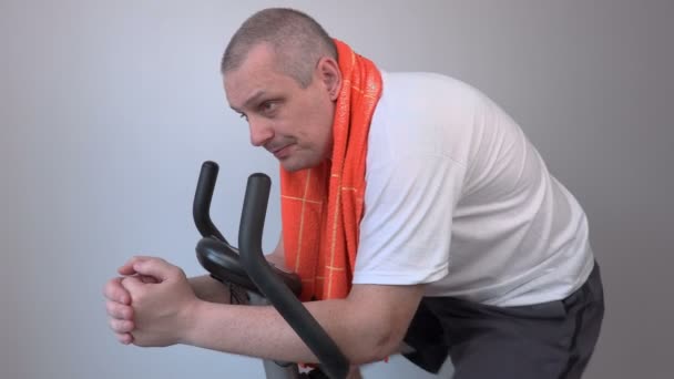 Focused man with a towel on exercise bike — Stock Video