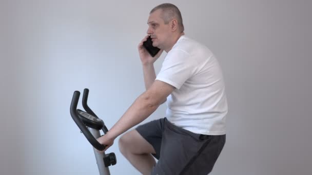 Мужчина разговаривает по смартфону и использует велосипед — стоковое видео