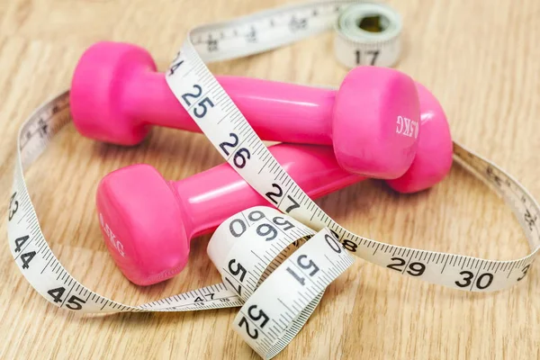 Dumbbells and tape measure on floor — Stock Photo, Image