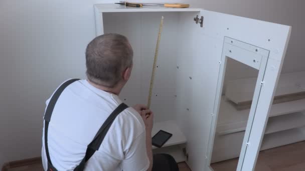 Чоловік використовує планшетний ПК біля меблів — стокове відео