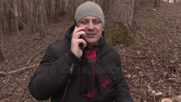 Мужчина разговаривает по телефону возле скворечника в парке — стоковое видео