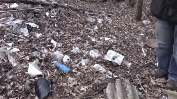 Hombre con pajarera hablando por teléfono cerca de basura en el bosque — Vídeo de stock