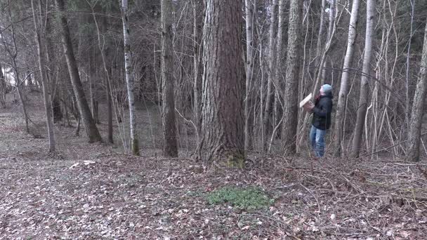 Мужчина пытается найти место для птичьего домика рядом с деревьями — стоковое видео