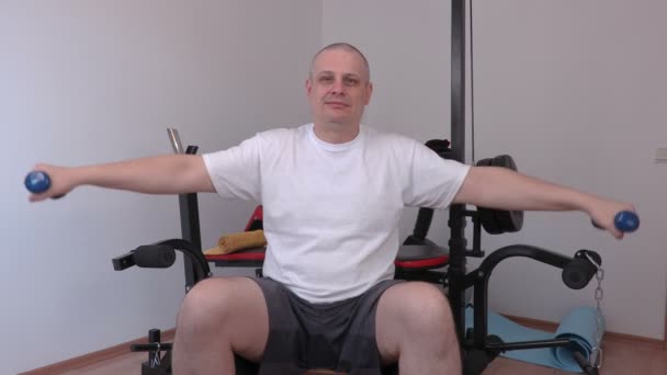 Человек с двумя маленькими гантелями делает упражнения для плеч — стоковое видео