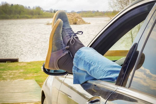 El hombre mantiene sus piernas a través de la ventana del coche —  Fotos de Stock