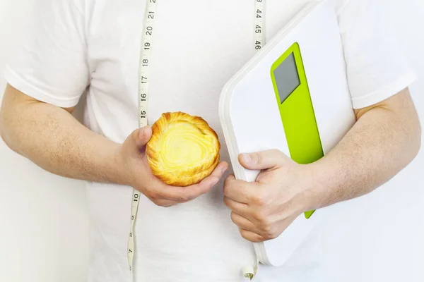 Человек с булочкой и цифровыми весами — стоковое фото