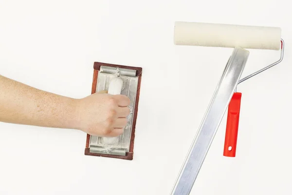 Hombre cerca de la pared con herramienta de molienda y rodillo de pintura en escaleras — Foto de Stock