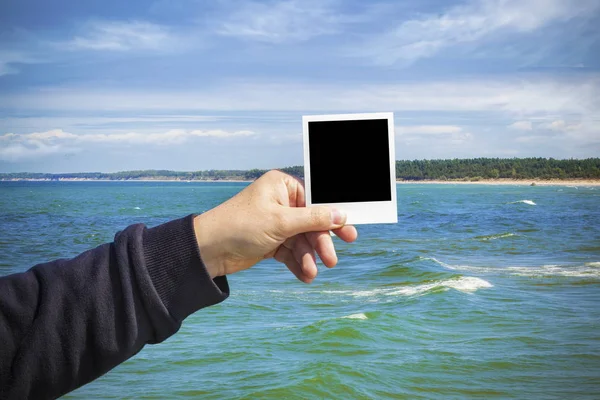Людина тримає фотографію на морському пейзажі — стокове фото