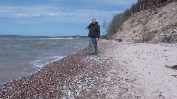 Человек поднимает янтарь вдоль берега моря — стоковое видео