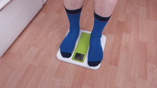 Чоловік піднімається в електронному масштабі і намагається виправити вагу — стокове відео