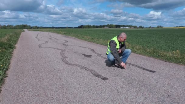 Kontrolleur misst mit Klebeband nahe Reifenspuren auf der Straße — Stockvideo