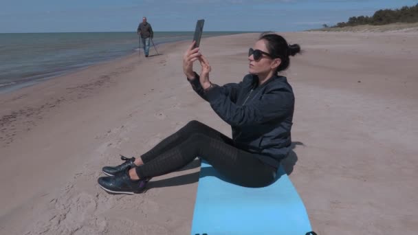 Žena sedí na pláži a pořizování selfie — Stock video