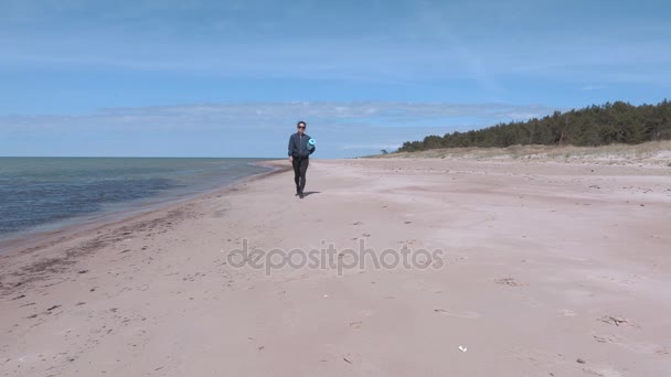 Mujer con colchoneta de entrenamiento caminando cerca del mar en un día ventoso — Vídeo de stock