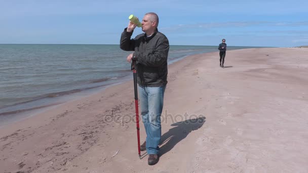 Турист с бутылкой воды на пляже у моря — стоковое видео