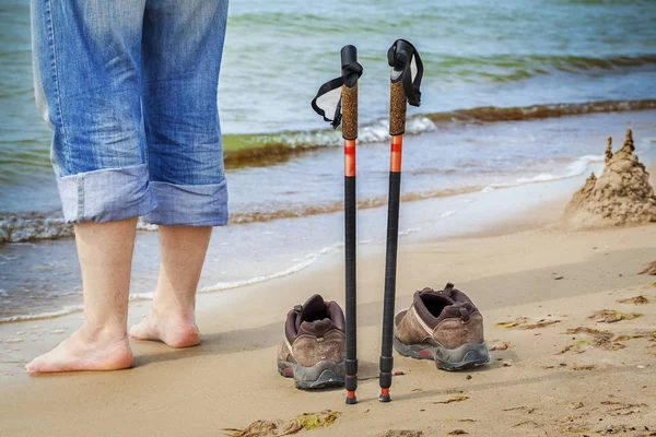 Hiking sticks with hiker in background near sea — Stock Photo, Image