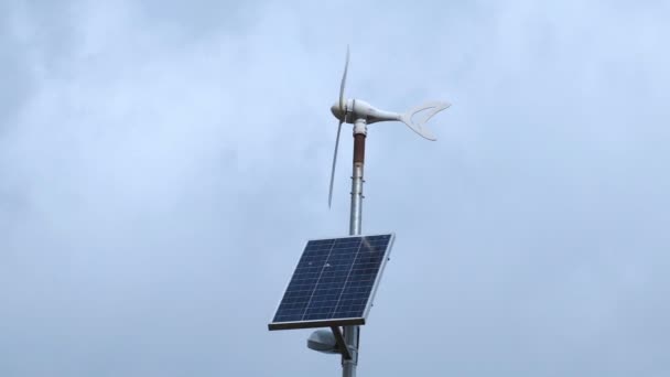 Vindgenerator med solpanel i blåsig och mulen dag — Stockvideo