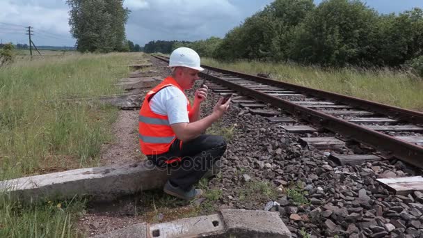 Železniční dělník na vysílačku seděl u zábradlí — Stock video