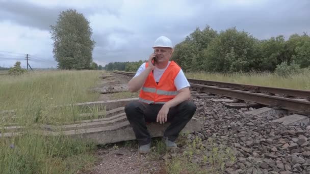 Vergadering van de spoorwegen in de buurt van railway en praten over de telefoon — Stockvideo