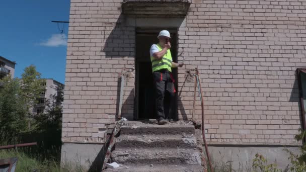 Bouwer op walkie talkie komt uit het gebouw — Stockvideo