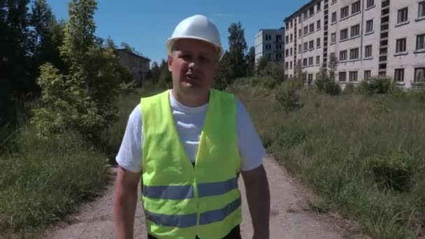 Construtor com walkie talkie andando na câmera e falando — Vídeo de Stock