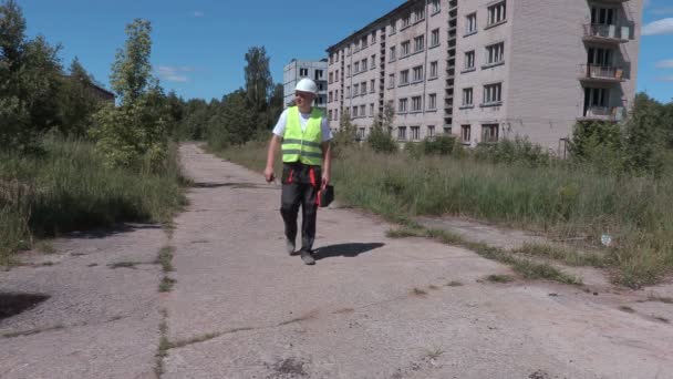 Builder poszukuje prawej drogę w pobliżu opuszczone domy mieszkalne — Wideo stockowe