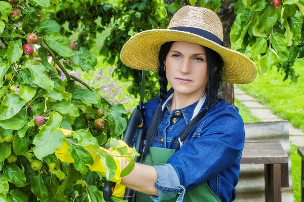 Vrouwelijke tuinman in stro hoed in de buurt van de appelboom — Stockfoto