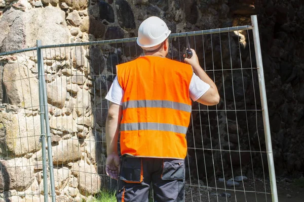 Constructor usando walkie talkie cerca de valla —  Fotos de Stock