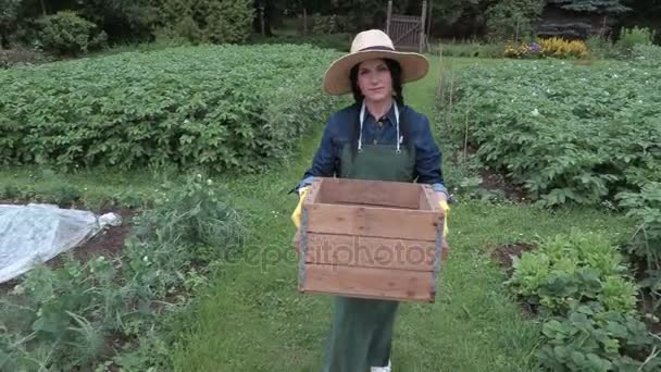 Θηλυκό κηπουρός μεταφέρουν κουτί στον κήπο — Αρχείο Βίντεο