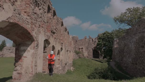 Costruttore che controlla le rovine di un vecchio castello — Video Stock