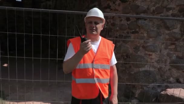 Camera gaat rond bouwer in de buurt van hek — Stockvideo