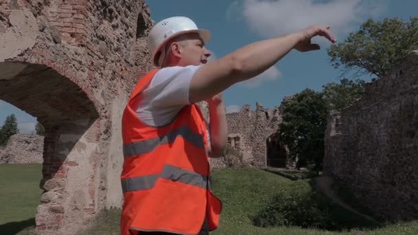 Constructor hablando y muestra gestos en el patio del castillo — Vídeo de stock