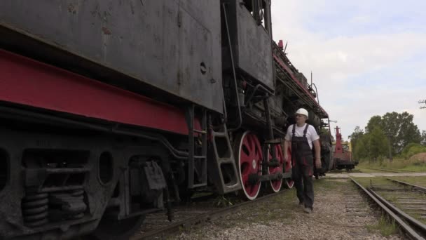 Сотрудник железной дороги говорит и идет рядом с локомотивом — стоковое видео