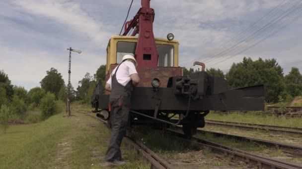 Сотрудник железной дороги идет вдоль поезда — стоковое видео